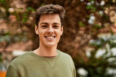 Şehirde kulaklık takarak mutlu gülümseyen genç İspanyol adam..