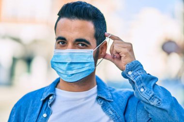 Genç İspanyol adam şehirde dikilerek tıbbi maske takıyor..