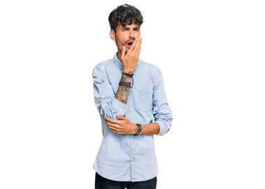 Gündelik kıyafetler giyen genç İspanyol adam ağzıyla ağzını kapatmaktan sıkılmış. Huzursuz ve uykulu.. 