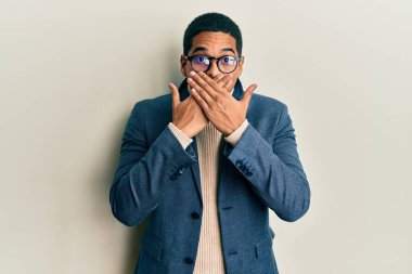 Zarif kıyafetler ve gözlük takan genç, yakışıklı İspanyol adam yanlışlıkla ağızlarını kapatarak şok etti. gizli kavram. 