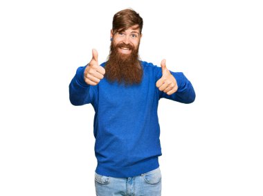 Genç İrlandalı kızıl saçlı, günlük giysiler giymiş, olumlu jestler yapıyor, gülümsüyor ve başarı için seviniyor. kazanan jest. 