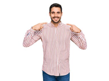 İş gömleği giyen, neşeli gülümseyen, parmaklarıyla ve ağzıyla işaret eden İspanyol bir genç. diş sağlığı kavramı. 