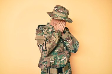 Genç yakışıklı adam, asker üniforması giyiyor. Ağlarken suratını ellerle kapatıyor. depresyon kavramı. 