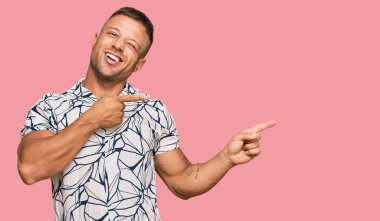 Yakışıklı, sıradan kıyafetler giyen, gülümseyen ve kameraya bakan kaslı bir adam.. 