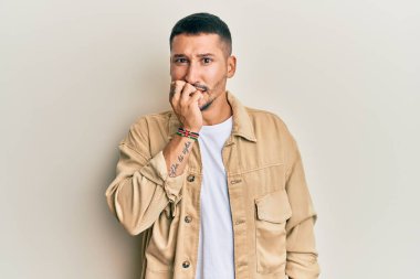 Günlük kahverengi kot ceket giyen yakışıklı bir adam gergin ve gergin görünüyor. Ağzı tırnak yiyen elleri var. anksiyete. 