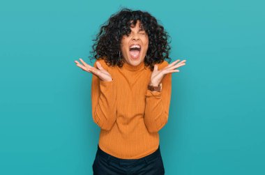 Gündelik kıyafetler giyen genç İspanyol kadın başarı için deli ve çılgınlığı kutluyor kollarını kaldırmış ve gözlerini kapatmış heyecanla bağırıyor. Kazanan konsept 