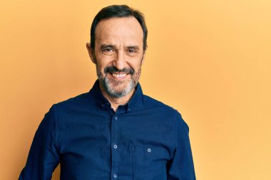 Orta yaşlı İspanyol bir adam mutlu ve havalı bir gülüşü olan sıradan kıyafetler giyiyor. şanslı kişi. 