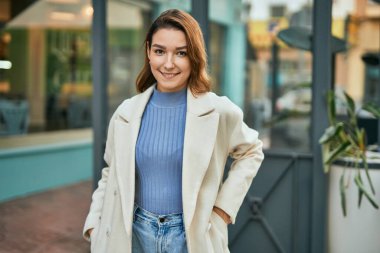 Genç İspanyol kadın gülümseyerek şehirde mutlu mesut dikiliyor.