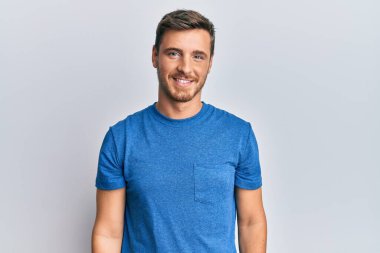 Yüzünde mutlu ve havalı bir gülümseme olan günlük kıyafetler giyen yakışıklı beyaz bir adam. şanslı kişi. 