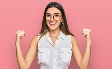 Gündelik kıyafetler giyen genç İspanyol kadın gururla bağırıyor, zaferi kutluyor ve kollarını kaldırıp başarıyı kutluyor. 