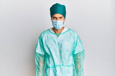 Cerrah üniforması giyen genç ve yakışıklı bir adam şüpheci ve sinirli, sorun yüzünden surat asıyor. negatif kişi. 