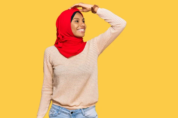 身穿传统伊斯兰头巾的年轻非洲裔美国女人面带微笑 自信地举起手触摸着头发 摆出迷人而时尚的架势 — 图库照片
