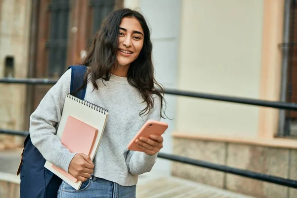 若いです中東学生女の子笑顔幸せな使用スマートフォンで市内 — ストック写真