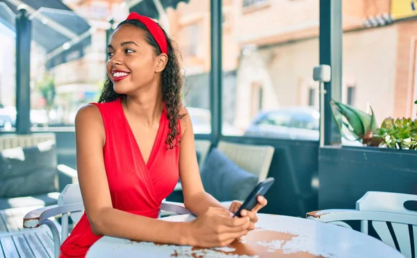 Chica Afroamericana Joven Sonriendo Feliz Usando Teléfono Inteligente Sentado Mesa —  Fotos de Stock