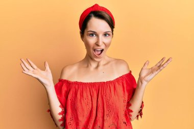 Kısa saçlı, kısa saçlı genç bir kadın zaferi kutluyor. Gülümsüyor ve elleri havada bir kazanan ifadesi var. 