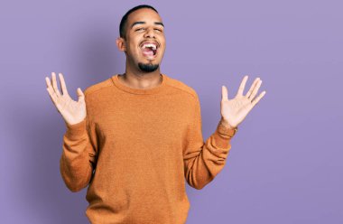 Genç afro-amerikan adam gündelik giysiler giyip çılgınlığı kutluyor ve başarıya hayret ediyor kolları açık ve gözleri açık heyecanla bağırıyor. Kazanan konsept 