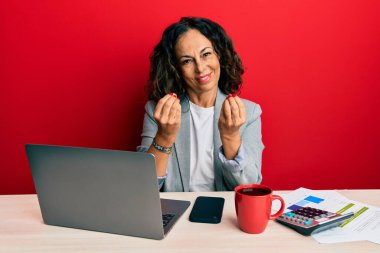 Ofiste çalışan orta yaşlı güzel bir kadın. Bir fincan kahve içiyor. Elleriyle para hareketi yapıyor. 