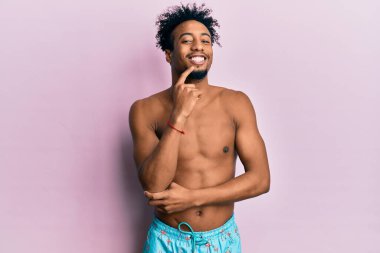 Sakallı, mayo giymiş, gülümseyen, kollarını kavuşturup çenesini kaldıran Afro-Amerikan bir adam. Olumlu düşünmek. 