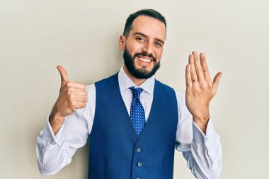 Nişan yüzüğü takan genç adam mutlu ve pozitif gülümsüyor, başparmağıyla mükemmel ve onay işareti yapıyor. 