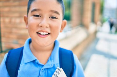 Sevimli öğrenci gülümsüyor. Şehrin caddesinde kitap tutarken mutlu..