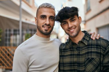 Mutlu bir şekilde gülümseyen ve şehirde sarılan genç eşcinsel çift..
