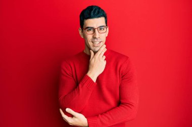 Sıradan kıyafetler ve gözlük takan yakışıklı İspanyol adam kameraya kollarını kavuşturup çenesini kapatarak gülümsüyor. Olumlu düşünmek. 