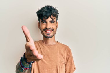 Gündelik kıyafetler giyen genç İspanyol adam dostça bir selamlama ve hoş geldin hediyesi olarak el sıkışmayı sunuyor. başarılı iş. 