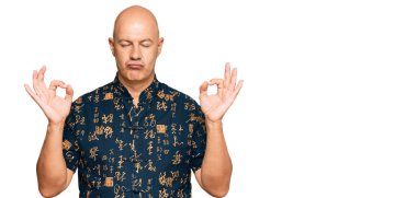 Orta yaşlı, kel, günlük kıyafetler giyen, gözleri kapalı gülümseyen, parmaklarıyla meditasyon yapan bir adam. yoga konsepti. 