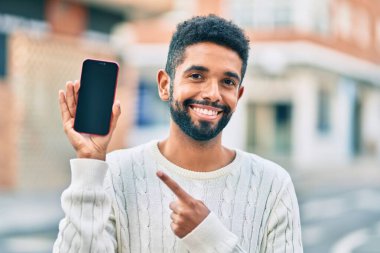 Genç Afrikalı Amerikalı adam gülümsüyor. Şehre akıllı telefon gösterdiği için mutlu..