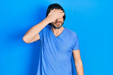 Orta yaşlı, günlük kıyafetler giyen, gülümseyen ve gülen bir beyaz adam şaşırmak için gözlerini kapatıyor. kör kavram. 