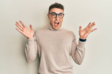 Balıkçı yaka kazak giyen İspanyol genç adam çılgın kutlamalar yapıyor ve kolları açık ve gözleri açık heyecanla haykırarak başarıya ulaşıyor. Kazanan konsept 