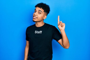 Asa tişörtü giyen genç Afro-Amerikan adam başarılı bir fikirle işaret ediyor. Heyecanlı ve mutlu. Bir numara.. 