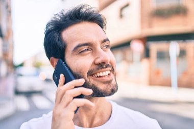 Genç İspanyol adam gülümsüyor. Şehirdeki akıllı telefondan konuşuyor..