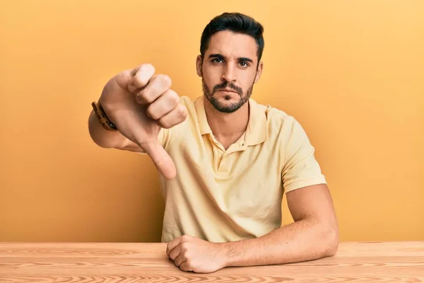 Joven Hombre Hispano Con Ropa Casual Sentado Mesa Mirando Infeliz —  Fotos de Stock