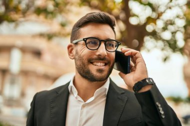 Genç İspanyol işadamı gülümsüyor. Şehirdeki akıllı telefondan mutlu bir şekilde konuşuyor..