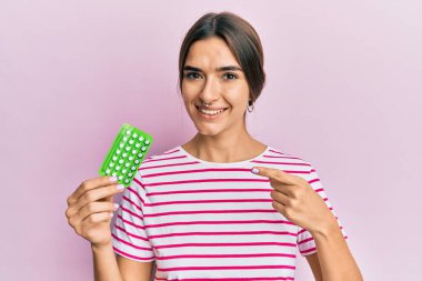 Elinde doğum kontrol hapları tutan genç İspanyol kadın mutlu bir şekilde elini ve parmağını gösterdi. 