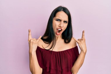 Genç İspanyol kadın gündelik kıyafetler giyip çılgın bir ifadeyle bağırıyor ve elleri havada rock sembolü yapıyor. Müzik yıldızı. ağır kavram. 