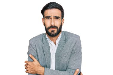 İş kıyafetleri giymiş genç İspanyol bir adam kışın soğuktan titriyor ve donuyor. Yüzünde üzgün ve şok ifadesi var. 