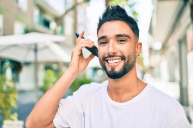 Genç Arap adam gülümsüyor. Şehirdeki akıllı telefonu kullanarak mutlu bir sesli mesaj dinliyor..