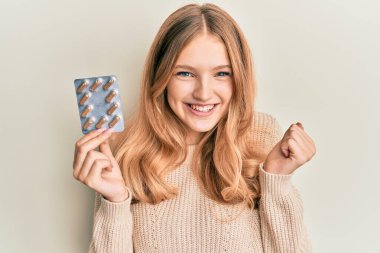 Güzel beyaz kız elinde haplarla gururla bağırıyor zaferi ve başarıyı kutluyor. 