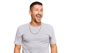 90 'lı yılların tarzı dövmeleri olan yakışıklı bir adam kameraya seksi bir ifadeyle bakıyor, neşeli ve mutlu bir yüzü var.. 