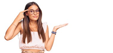 Gündelik kıyafetler giyen ve gözlük takan genç İspanyol kadın avuç içi açık fotokopi alanı ve alnını göstermekten rahatsız oluyor. Bunu bir düşün.. 