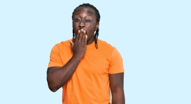 Yakışıklı, Afro-Amerikalı, günlük kıyafetler giyen, ağzı eliyle kapatmaktan sıkılmış, esnemekten sıkılmış. Huzursuz ve uykulu.. 