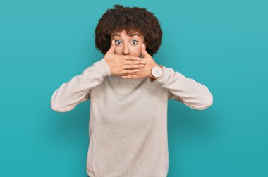 Yün kazak giyen genç İspanyol kız yanlışlıkla elleriyle ağzını kapatırken şok oldu. gizli kavram. 