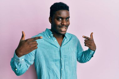 Yakışıklı, gündelik kıyafetler giyen, neşeli gülümseyen, parmaklarıyla ve ağzıyla işaret eden siyahi bir adam. diş sağlığı kavramı. 