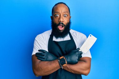 Profesyonel önlük giymiş genç Afro-Amerikan bir adam elinde bıçak tutarken şaşkınlık ve şaşkınlık dolu bir ifade, korku ve heyecanlı bir yüz ifadesiyle şoka girdi.. 