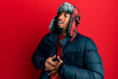 Sakallı, kışlık şapkalı ve eli karnında paltosu olan Afrikalı genç bir Amerikalı. Çünkü mide bulantısı, acı verici bir hastalık kendini iyi hissetmiyor. Ağrı kavramı. 