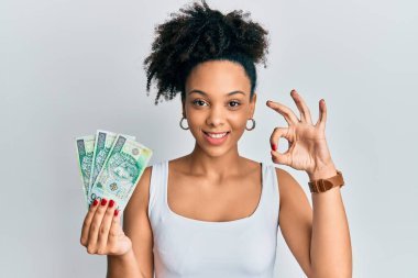 Genç Afro-Amerikalı kız elinde 100 Polonya parası tutuyor. Parmaklarıyla imza atıyor, gülümsüyor. Mükemmel bir sembol. 