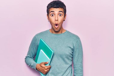 Genç Afrikalı Amerikalı bir adam elinde kitap tutuyor. Korkmuş ve ağzı açık kalmış, şaşırmış ve şaşırmış. 