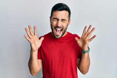 Gündelik kıyafetler giyen genç İspanyol adam başarı için deli ve çılgınlığı kutluyor kollarını kaldırmış ve gözlerini kapatmış heyecanla bağırıyor. Kazanan konsept 